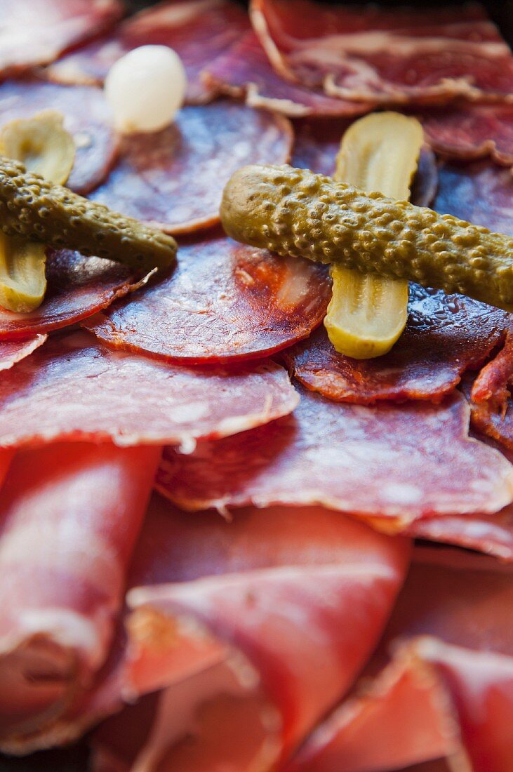 Platter of sliced sausage with pickled gherkins (Italy)