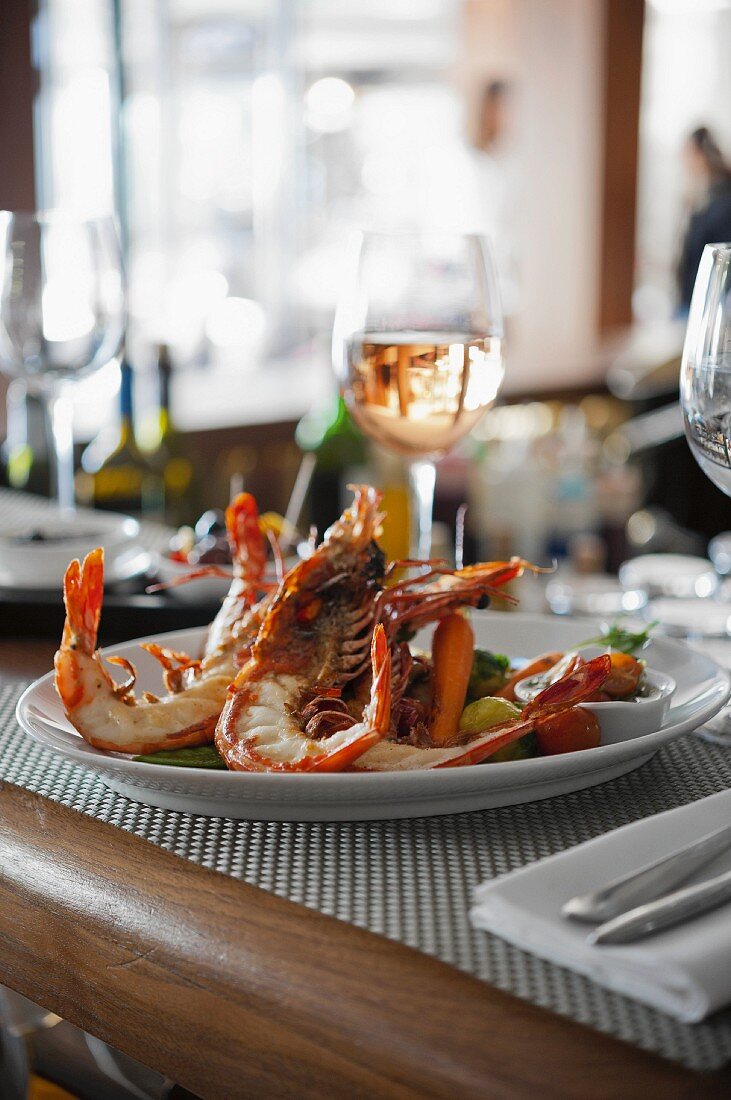 King prawns with vegetables and wine on a restaurant table