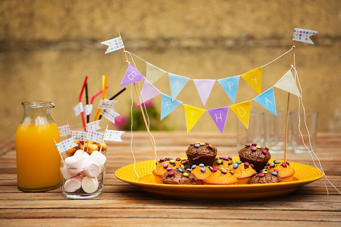 Muffins mit Schokolinsen, Marshmallows und Orangensaft für Kindergeburtstag