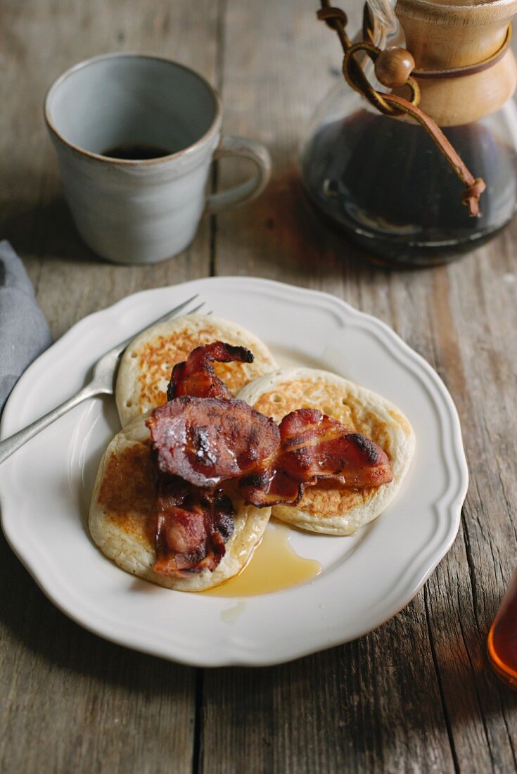 Pancakes mit Bacon und Ahornsirup; dazu Kaffee