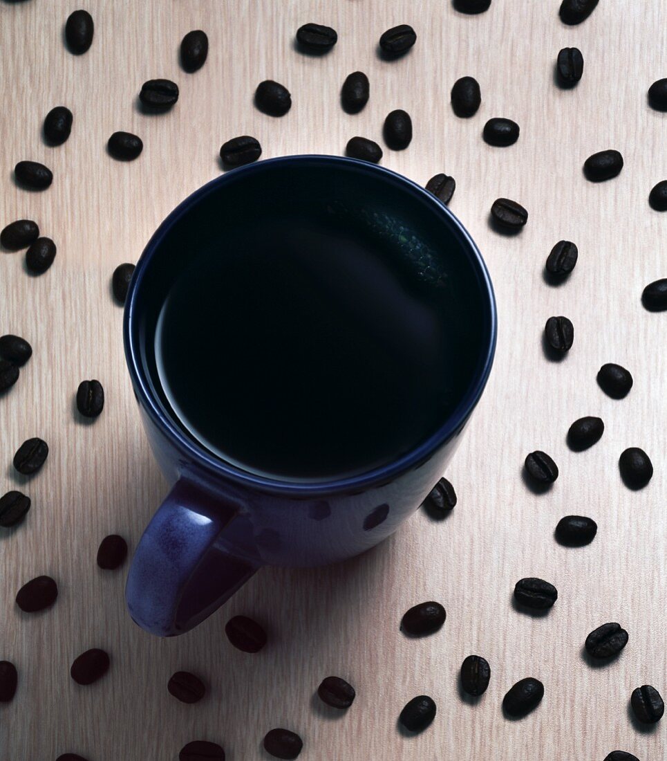 A Cup of Black Coffee Surrounded by Coffee Beans