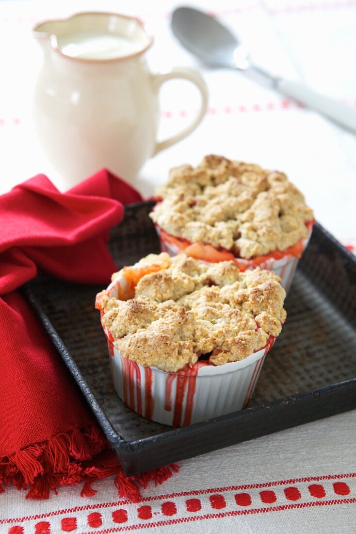 Raspberry and apple crumble cooling on a tray served with a jug of custard