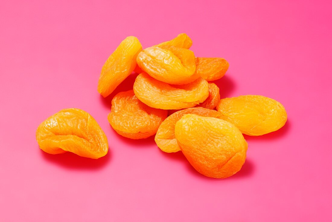Dried apricots on a bright pink surface