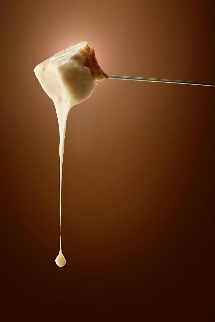 Fondue cheese dripping from a fork