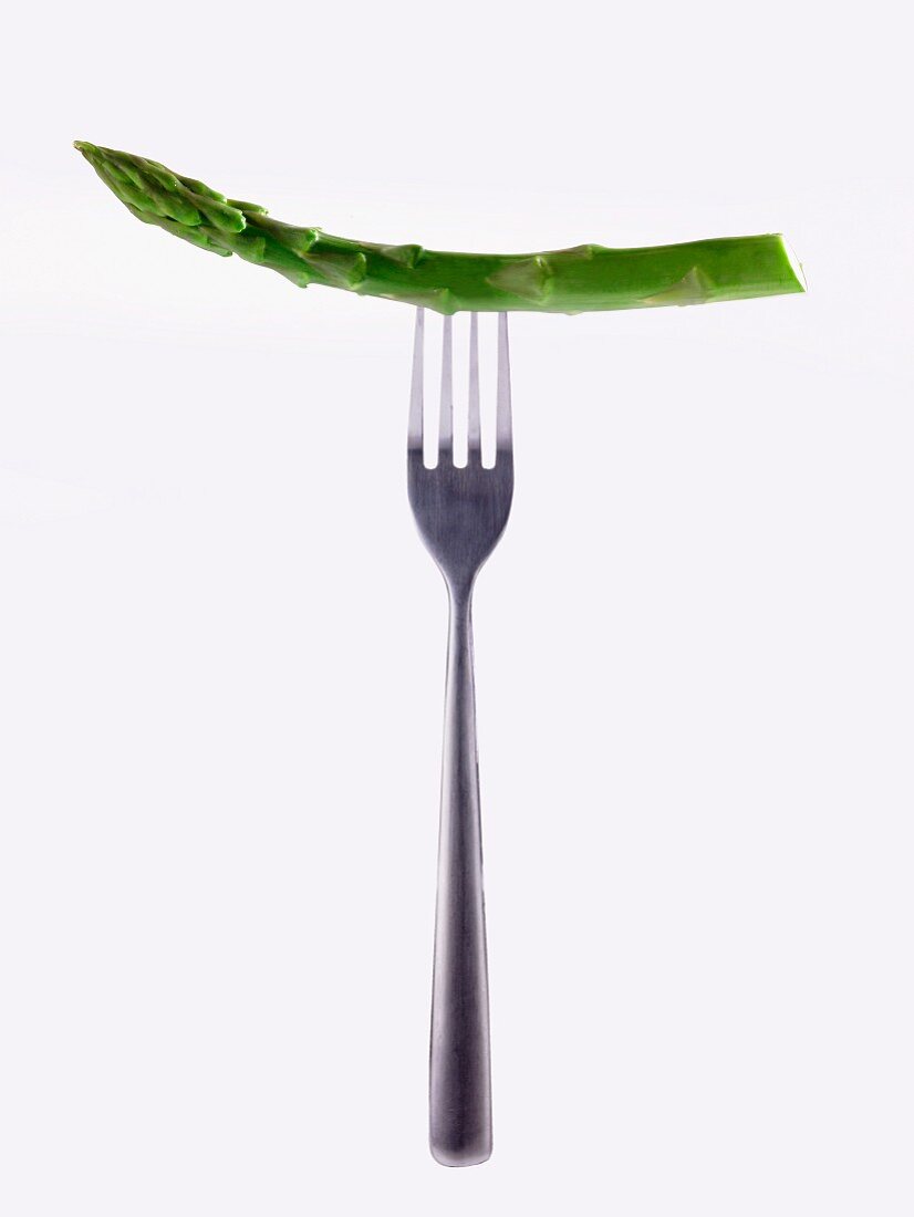 A stem of green asparagus on a fork