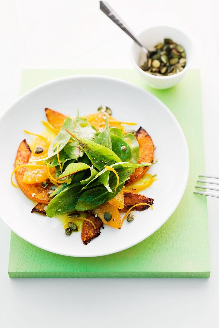 Spinach salad with squash, orange and pumpkin seeds