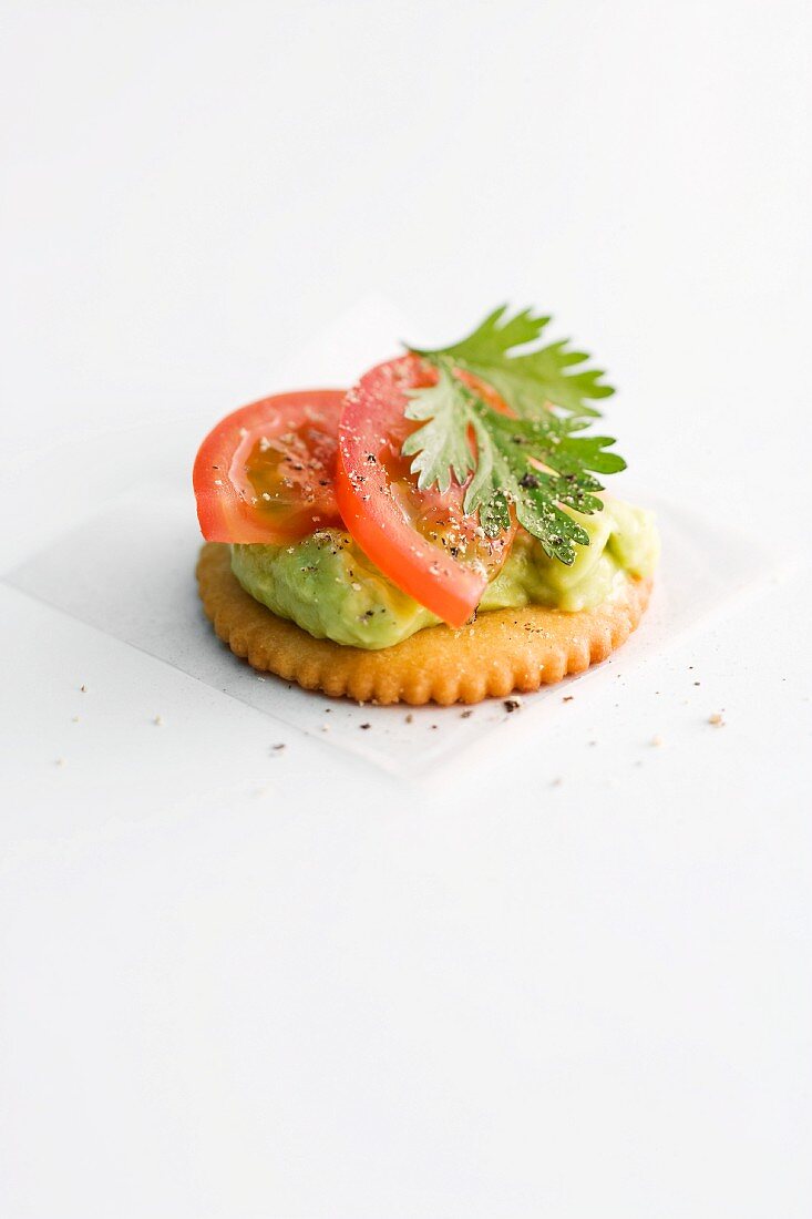 A cracker topped with avocado pur