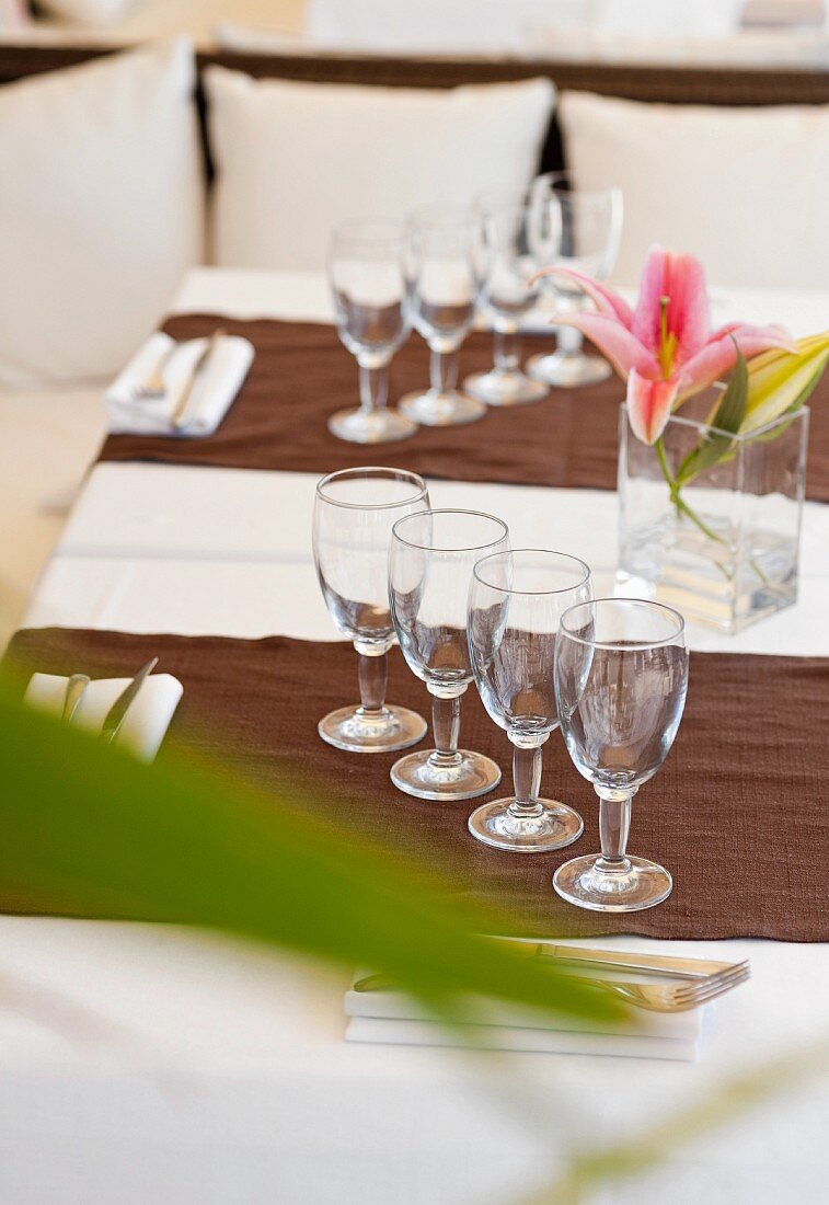 Gläser, Servietten, Besteck und Lilien auf Restauranttisch