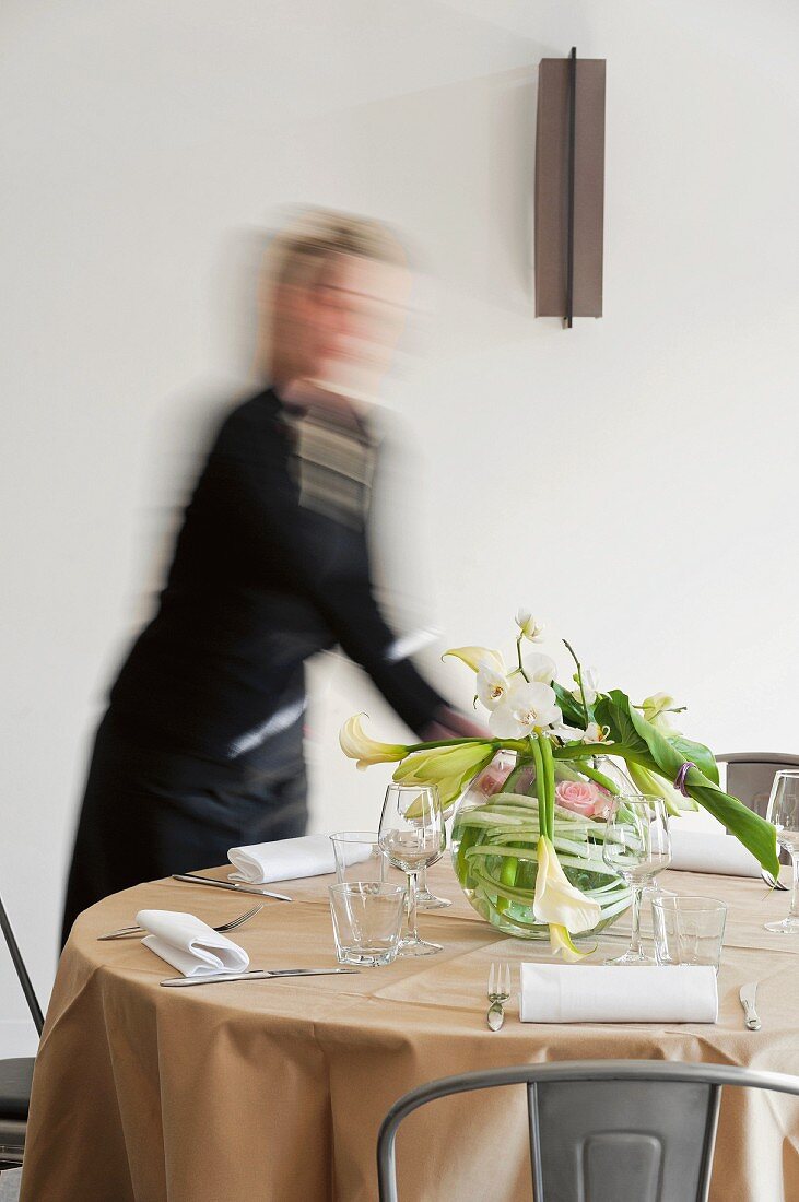 A woman arranging flowers on a restaurant table