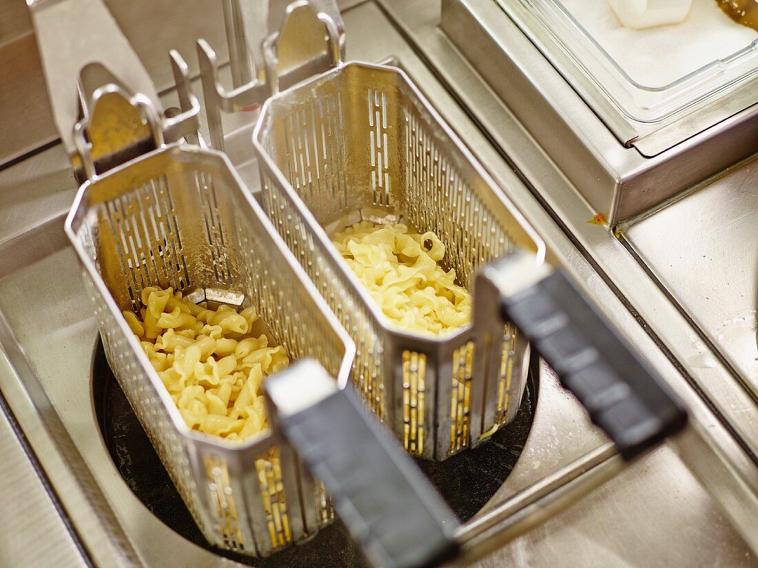 Containers of boiled pasta in a commercial kitchen
