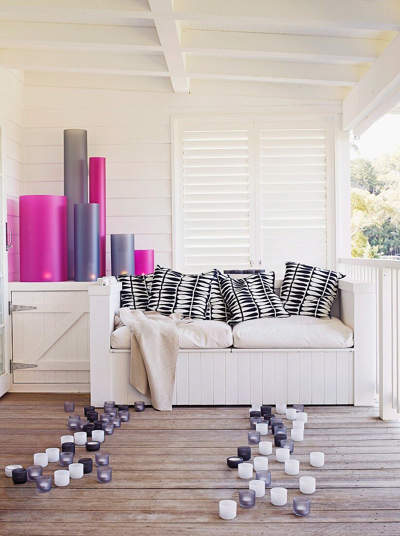 Multicoloured candle lanterns and bench with cushions on roofed terrace