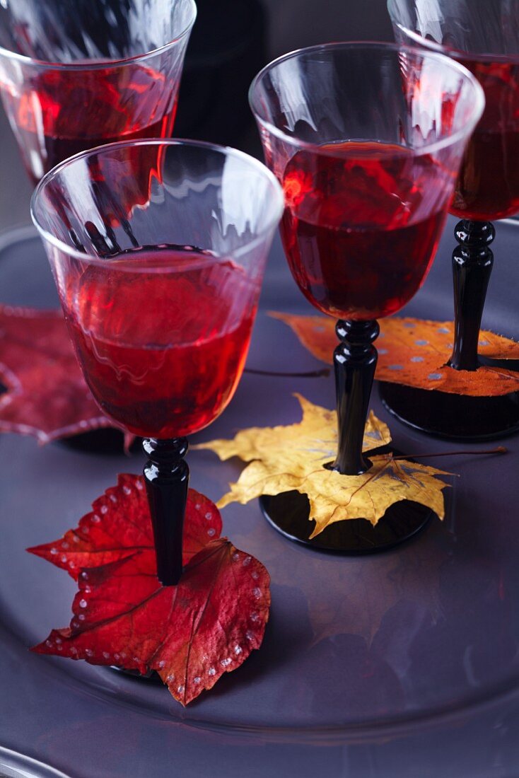 Weingläser dekoriert mit bunten, bemalten Herbstblättern