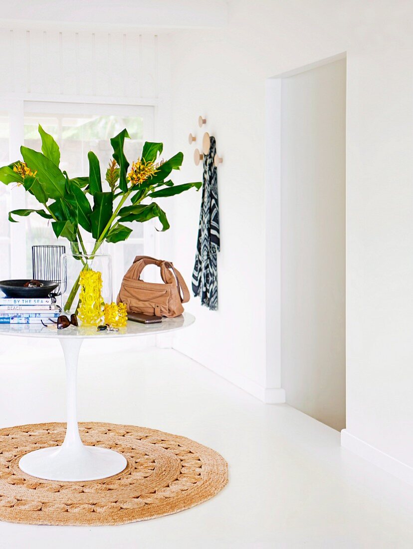 White tulip table with flowers, handbag and books on a round natural fiber carpet