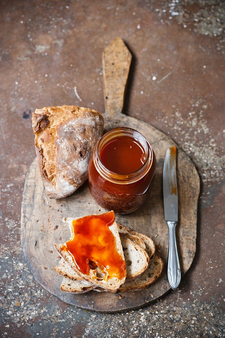 Hagebuttenmarmelade und Brot auf Schneidebrett