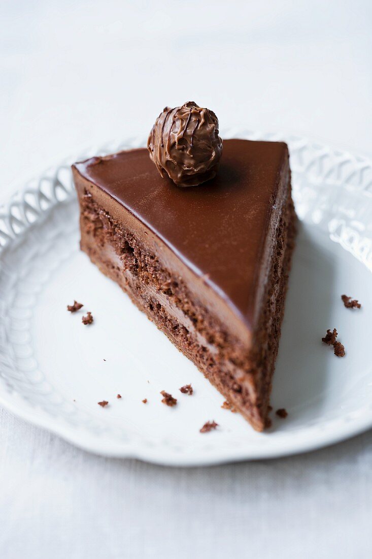A slice of chocolate layer cake topped with a filled chocolate