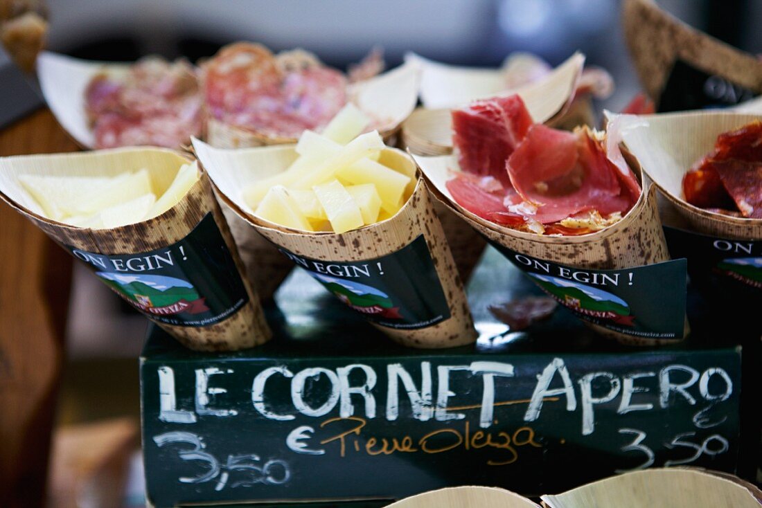 A market stall with cheese, ham and sliced sausage in paper cones