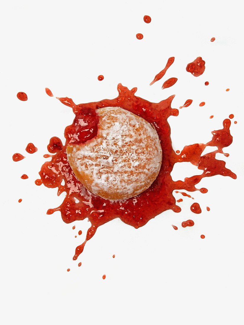 A dropped doughnut; jam has squirted out in all directions