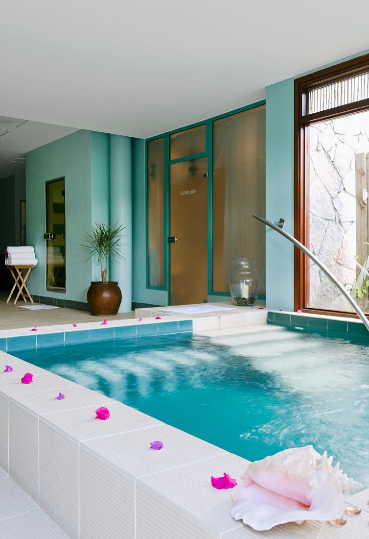 Wellness pool decorated with flowers and shells, turquoise walls in a spa area