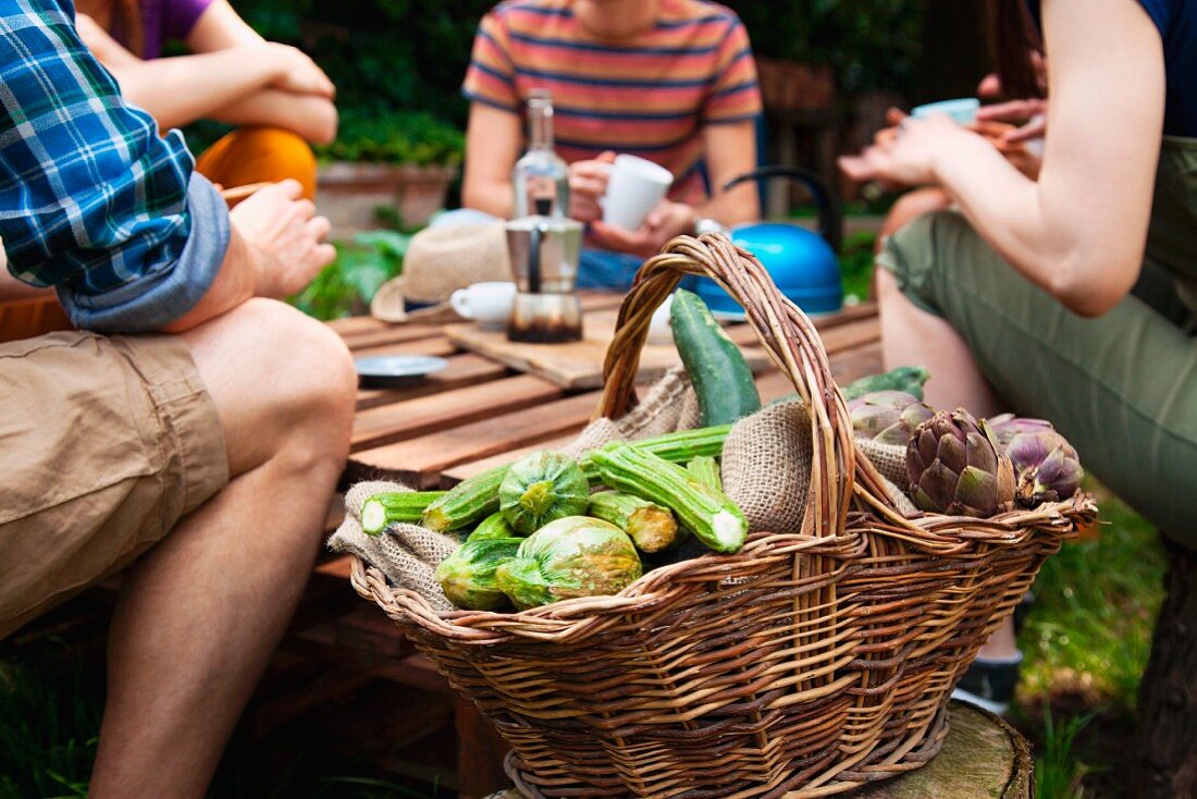 Korb mit frischem Gemüse, im Hintergrund Gruppe junger Leute