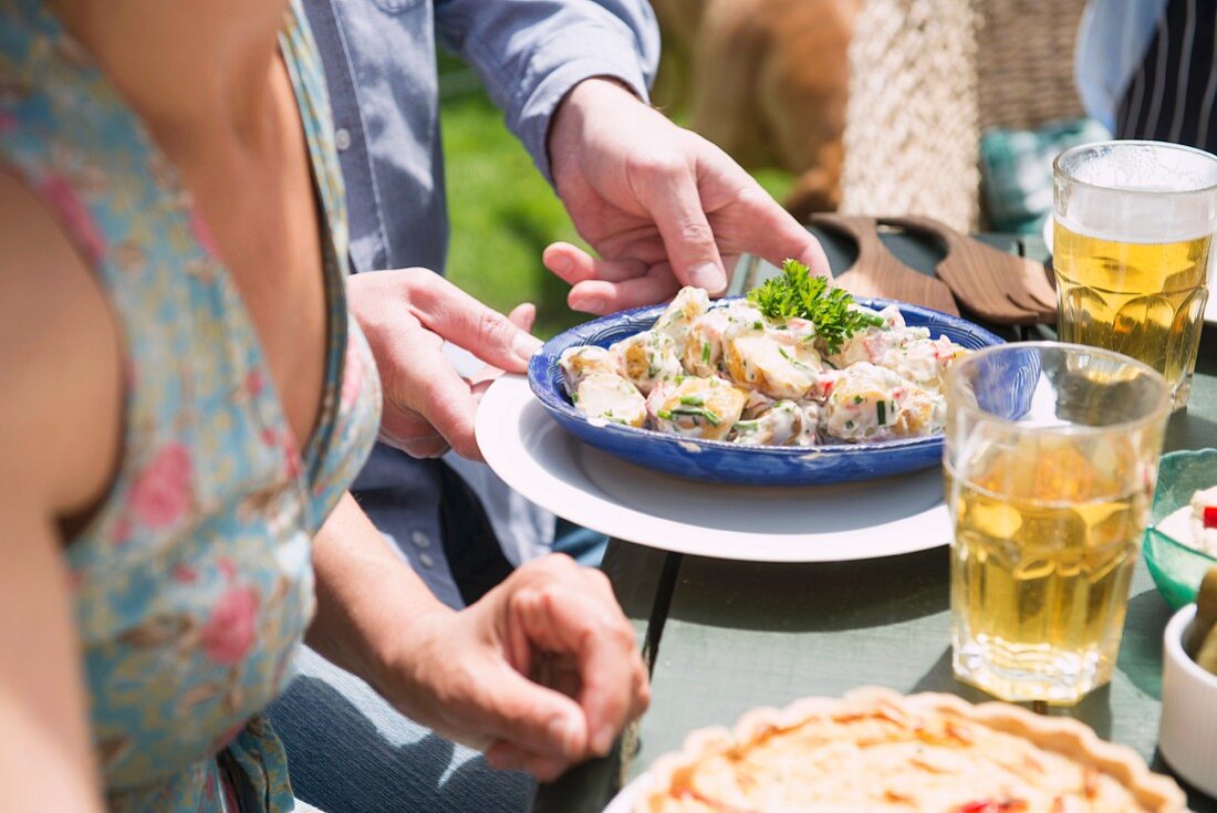 Several people having a meal at a table in the garden (close-up)