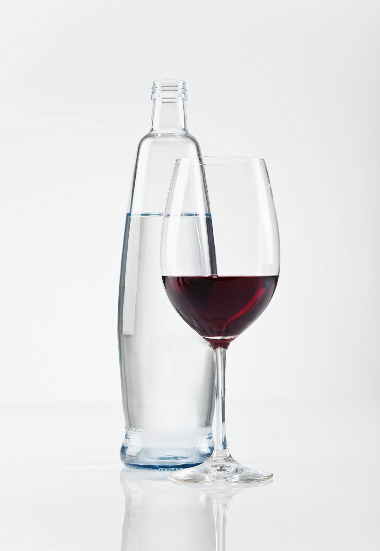 A glass of red wine next to a bottle of water