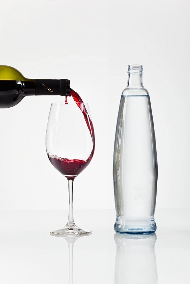 Rotwein einschenken neben einer Wasserflasche