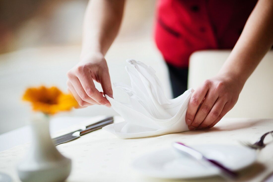 A waitress folding a napkin