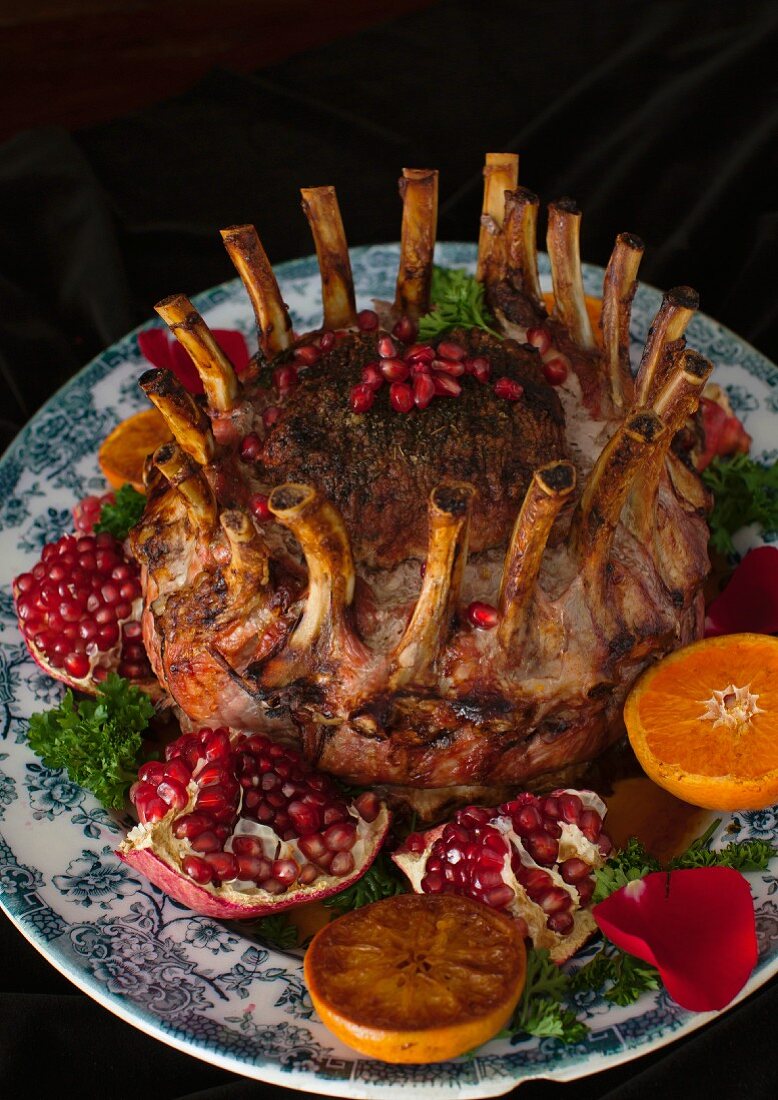 Crown roast of pork on a black background with fruits