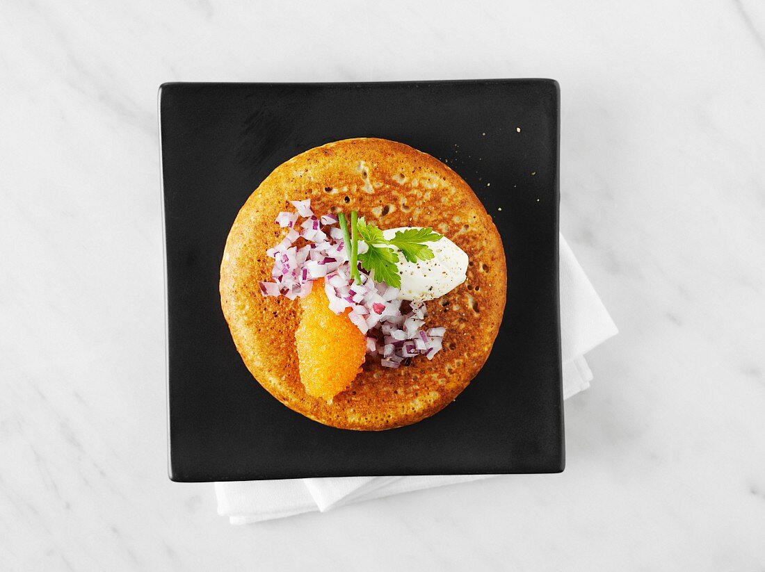Blini topped with caviar, onion and sour cream