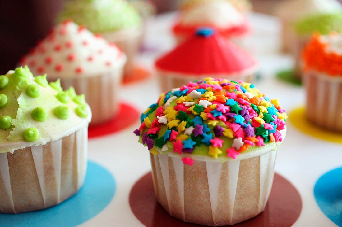 Multi-colored cupcakes on a tray, focus on cupcake with rainbow star sprinkles