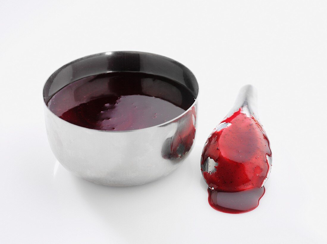 Berry sauce in a metal bowl and on a spoon