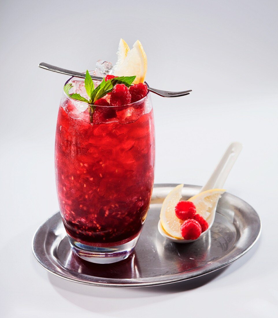 Fruchtcocktail mit Himbeeren und Minze auf Silbertablett