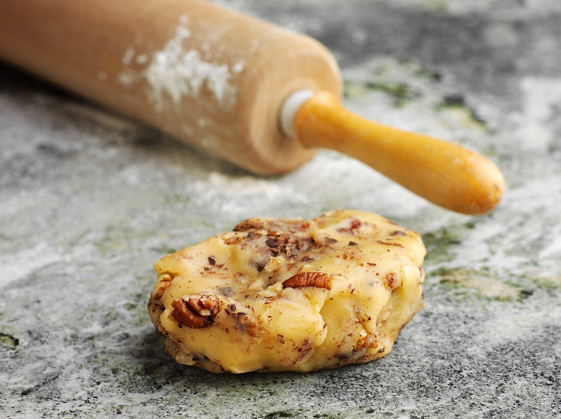 Cake dough with nuts next to a rolling pin