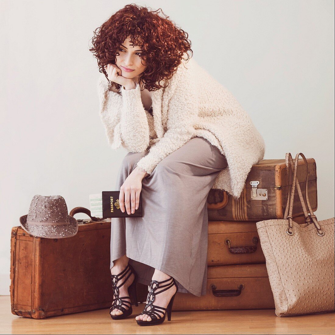 Fashionably dressed young woman sitting, waiting, on suitcases