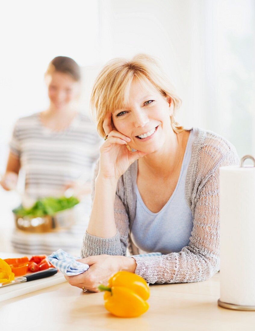 A mother and her adult daughter cooking in the kitchen