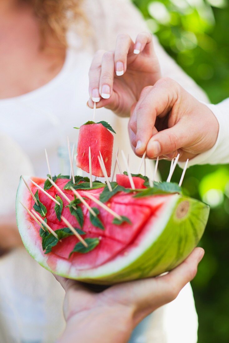 Guests at a garden party eating watermelon on sticks