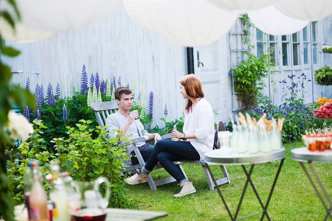 Junges Paar unterhält sich beim Sommerfest im Garten