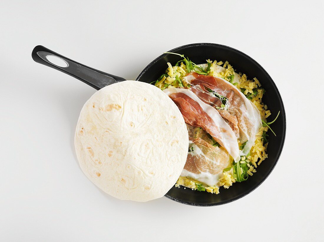 Tortilla in a frying pan with ham and cheese (view from above)