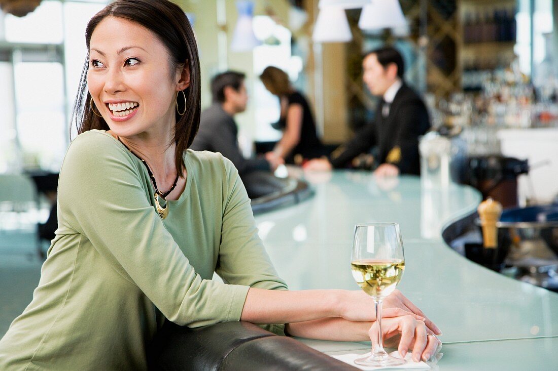 Frau an der Bar mit einem Glas Wein