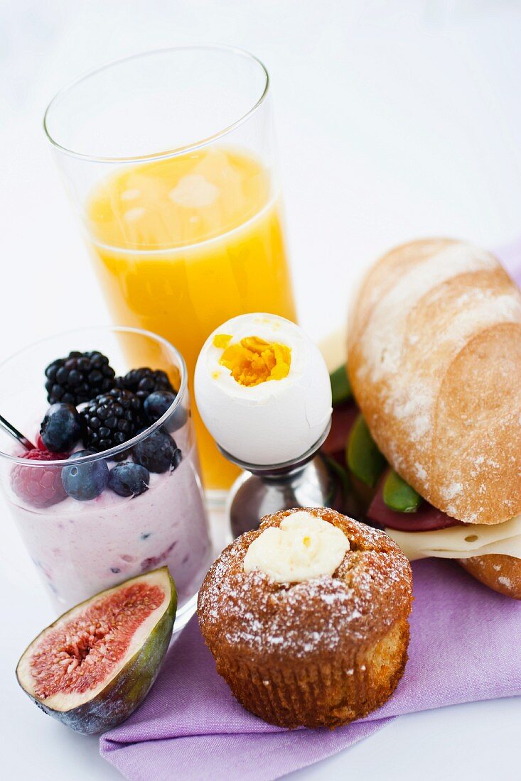 Frühstück mit Orangensaft, Ei, Joghurt, Sandwich & Muffin