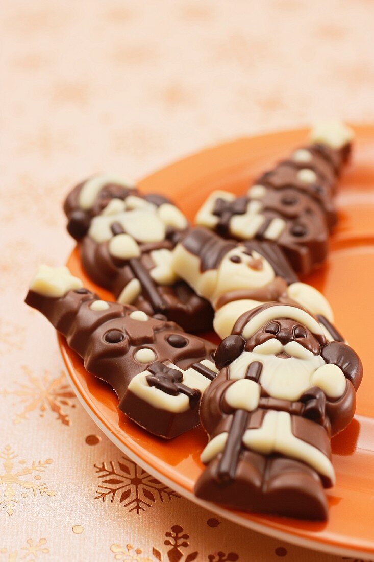 Schokoladennikoläuse und Schokoladenchristbäume auf Teller