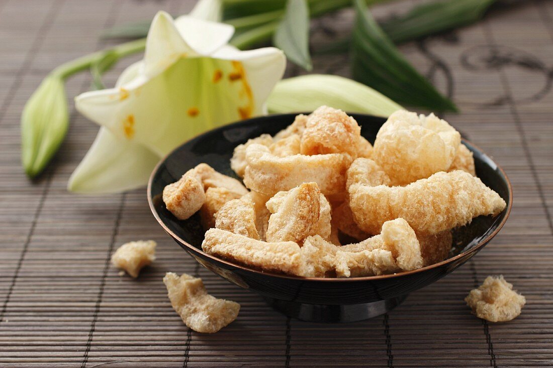 Crispy bacon rinds in front of a lily