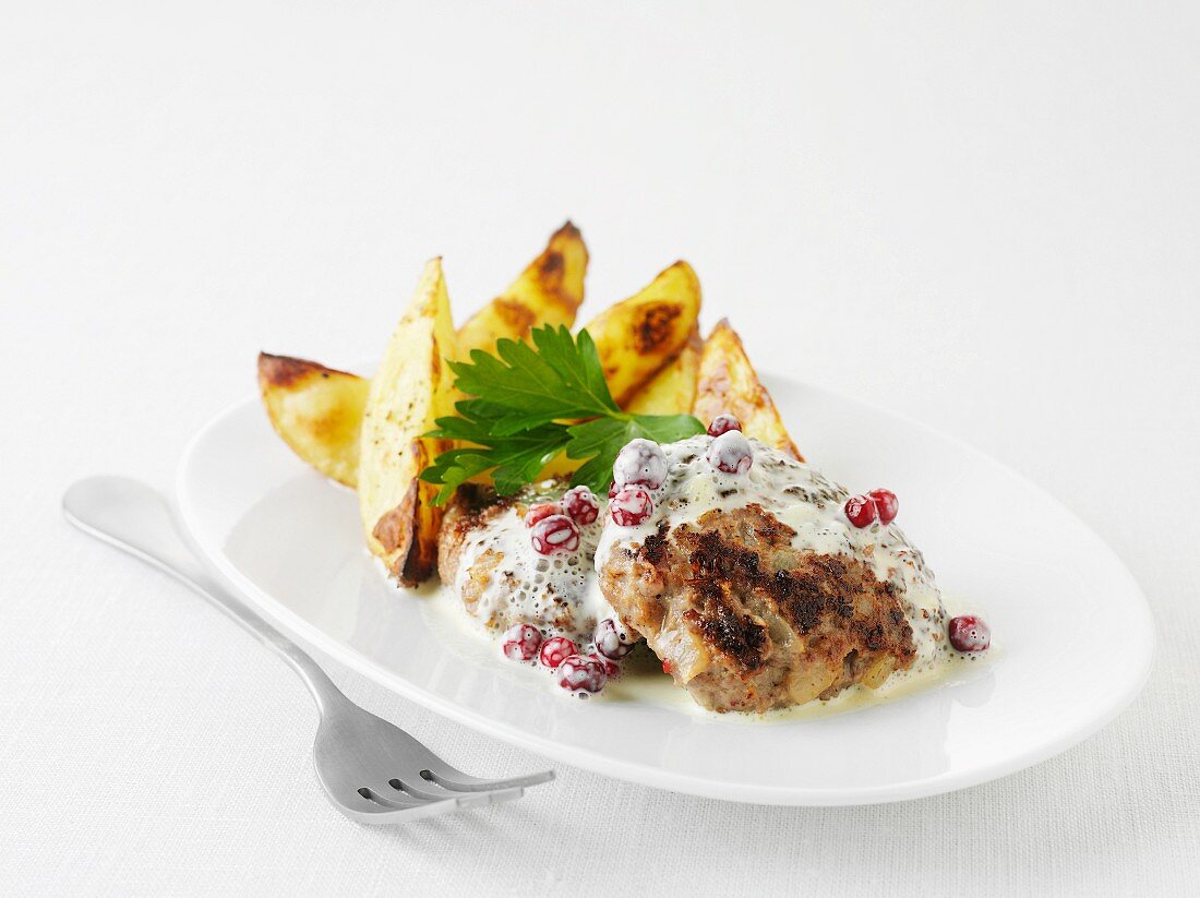 Burgers with cranberries in a cream sauce with potato wedges (Sweden)