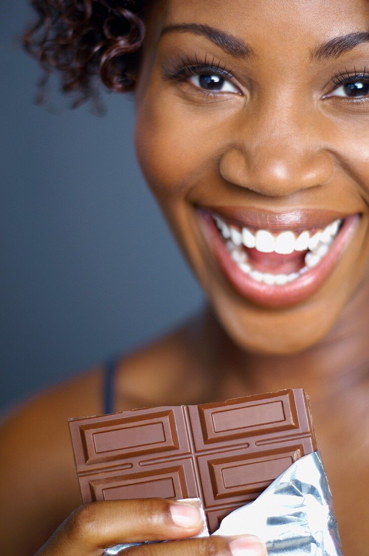 African woman eating chocolate bar