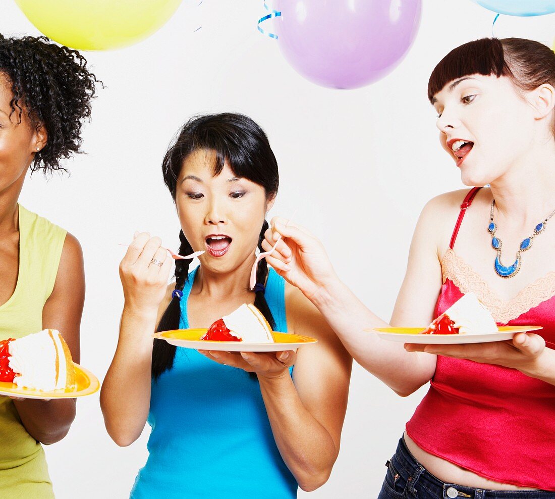 Drei Freundinnen essen Torte auf einer Party