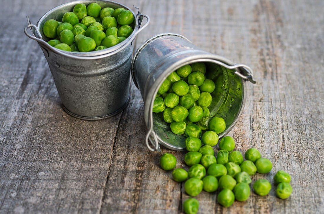 Peas in a bucket of brass on wooden background
