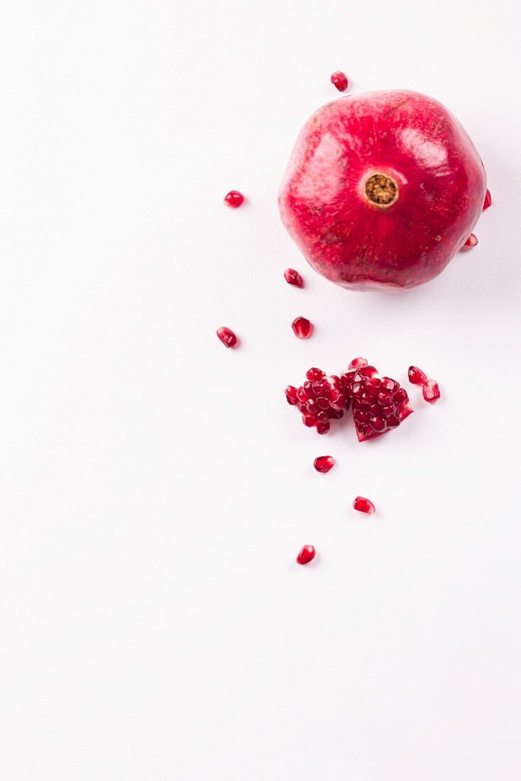 A whole pomegranate, pomegranate seeds and chunks of pomegranate