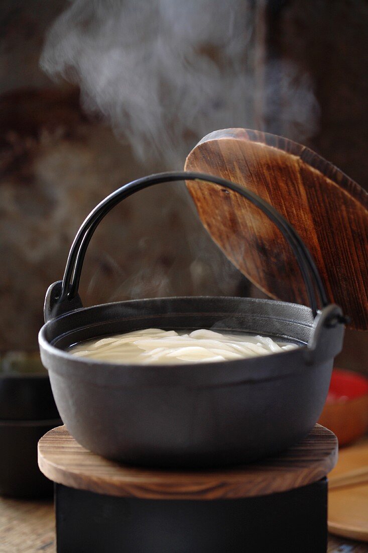 Steaming pot of soup with udon noodles