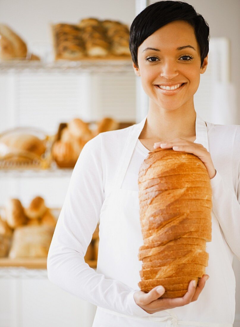 Junge Frau mit geschnittenem Brotlaib in der Hand
