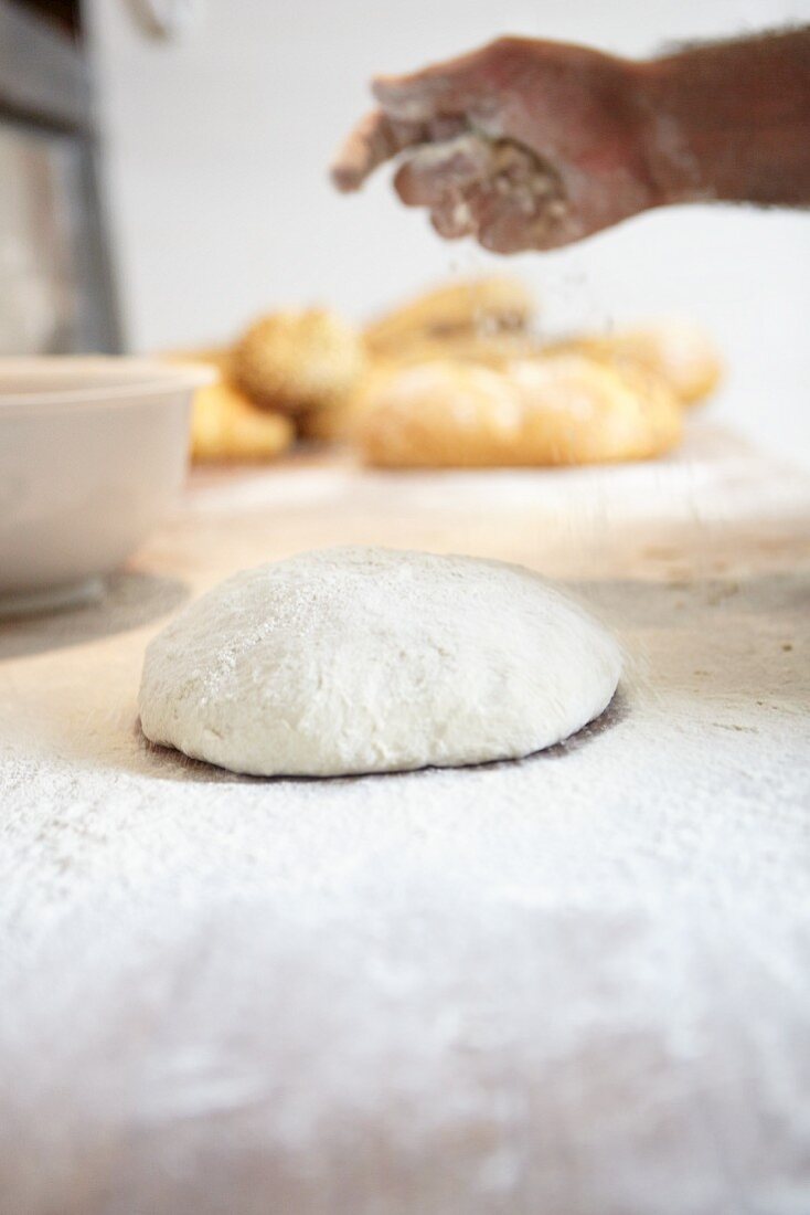 A baker scattering flour over bread dough